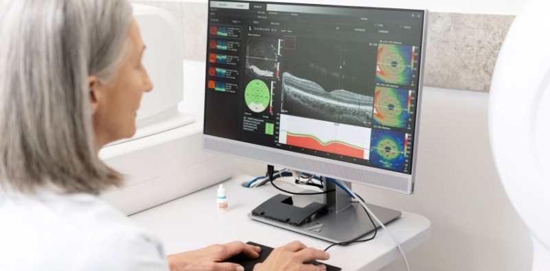 An eye doctor analyzing an OCT scan on a computer