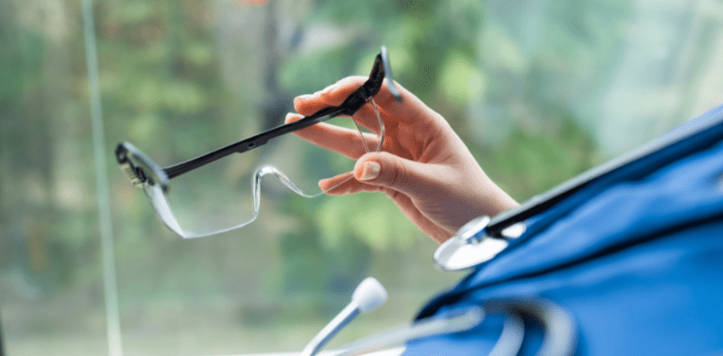 A doctor holding a pair of glasses for protection