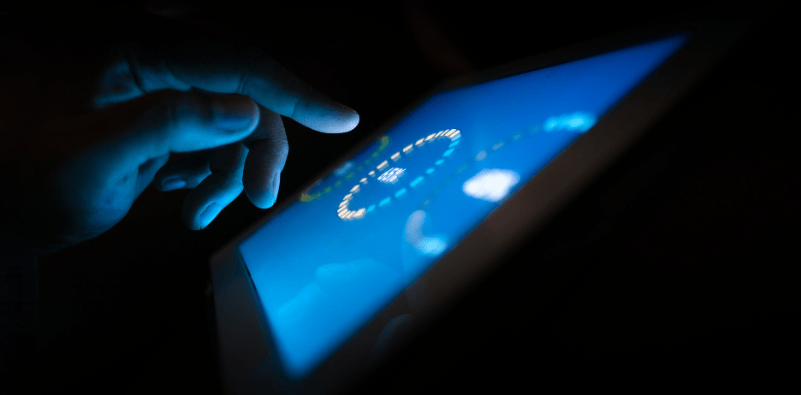 A woman wearing glasses at the desk with a laptop on the side