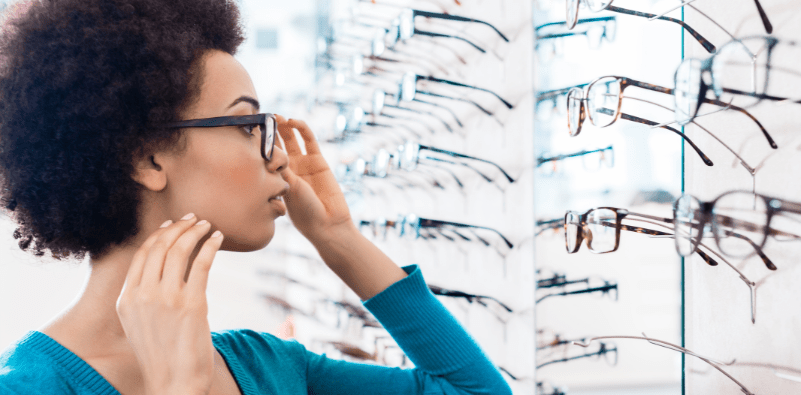 A woman trying on glasses from a rack at an eye doctor office