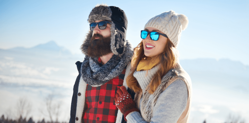 A couple, outdoors during winter, wearing sunglasses